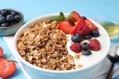 Böğürtlenli ve yoğurtlu leziz granola açık mavi masada, yakın plan.