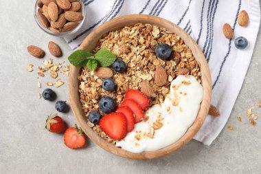 Böğürtlenli tahıl gevreği, badem ve yoğurt kasede gri desenli masada, düz yerde.