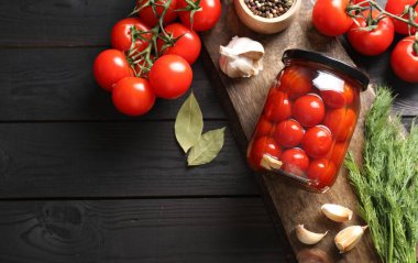 Kavanozda domates turşusu, baharatlar ve taze sebzeler. Gri ahşap masa, üst manzara. Metin için boşluk