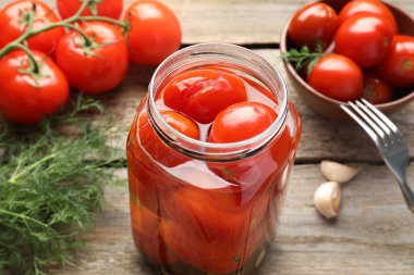 Lezzetli domates turşusu, baharatlar, taze sebzeler ve ahşap masa çatalı, yakın plan.