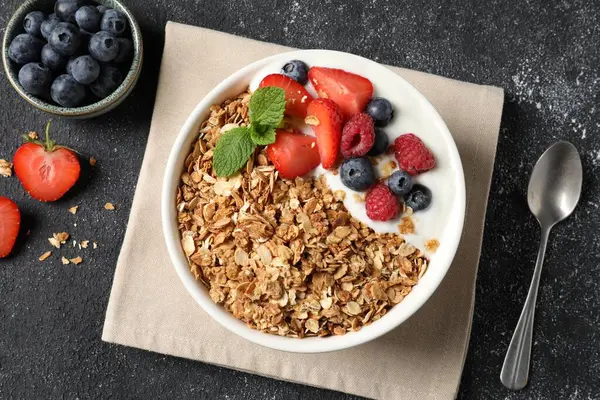 Koyu dokulu masada servis edilen böğürtlenli ve yoğurtlu lezzetli granola.