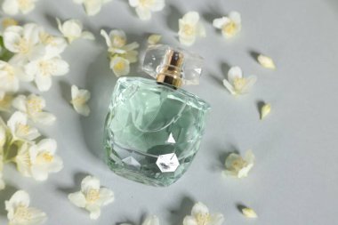 Şişede Aromatik parfüm ve gri arka planda güzel yasemin çiçekleri.