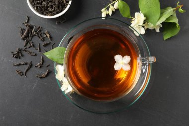 Cam bardakta Aromatik yasemin çayı, gri masada çiçekler ve kuru yapraklar, üst manzara