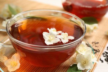 Sıcak yasemin çayı fincanda ve çiçekler beyaz ahşap masada, yakın plan