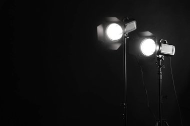 Karanlık fotoğraf arkaplanı ve profesyonel ışıklandırma ekipmanları stüdyoda. Metin için boşluk