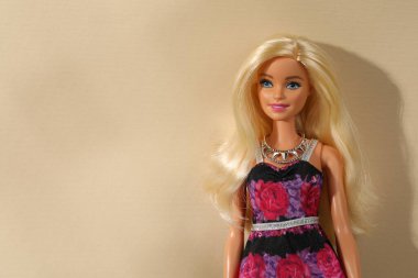 Mykolaiv, Ukrayna - 4 Eylül 2023: Bej arka planda kolye takan güzel Barbie bebek, metin için yer