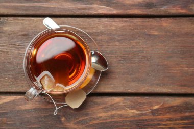 Aromatik çay demliyorum. Tahta masada çay poşeti ve kaşık, üst manzara. Metin için boşluk