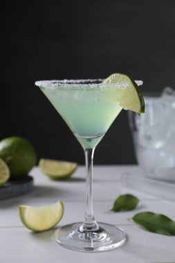 Lezzetli Margarita kokteyli ve beyaz ahşap masada limon.