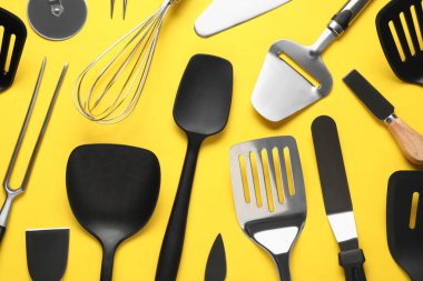 Sarı arka planda farklı spatulalar ve diğer mutfak aletleri, düz konum