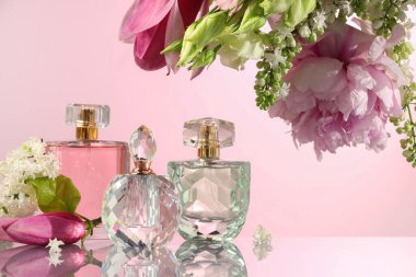 Ayna yüzeyinde pembe arka planda lüks parfümler ve çiçek dekoru