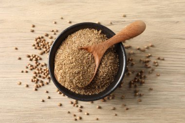 Kasede kişniş tozu, tahta masada kaşık ve tohumlar, üst manzara.