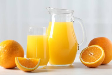 Lezzetli portakal suyu ve beyaz ahşap masada taze meyveler.