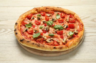 Domatesli, mantarlı ve ahşap masadaki fesleğenli lezzetli pizza.