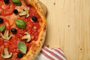 Domatesli, mantarlı, siyah zeytinli ve ahşap sehpada fesleğenli lezzetli pizza. Metin için boşluk