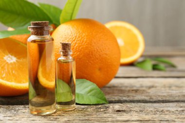 Temel yağlar şişe, portakal ve yeşil yapraklar ahşap masa üzerinde, metin için boşluk