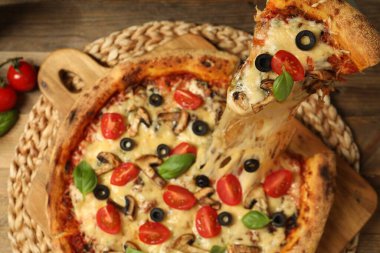 Ahşap masada erimiş peynirli lezzetli bir pizza yemek.