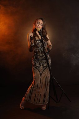 Mikrofonlu güzel genç bir kadın. Renkli ışıklar ve dumanlar içinde şarkı söylüyor.