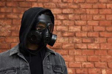 Dışarıdaki kırmızı tuğla duvarın yanında gaz maskeli bir adam var. Metin için boşluk