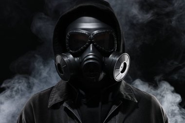 Siyah arka planda gaz maskesi takan adam.