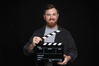 Film çekiyoruz. Siyah arka planda alkışlarla gülümseyen adam.