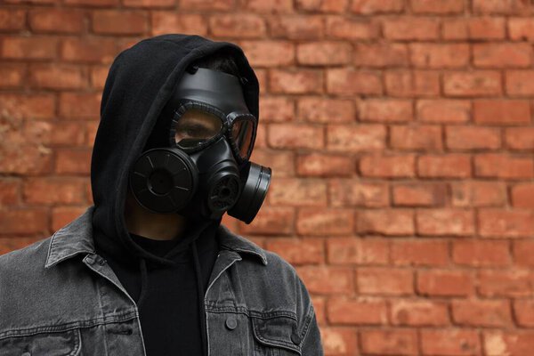 Человек в противогазе возле стены из красного кирпича. Пространство для текста