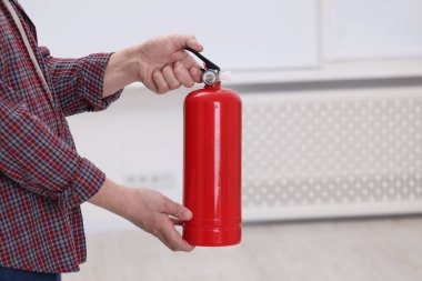 Kapalı mekanda yangın söndürücü olan adam, yakın plan. Metin için boşluk
