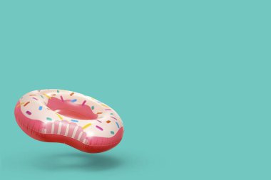 Havada turkuaz arka planda şişirilebilir halka şeklinde bir donut. Metin için boşluk