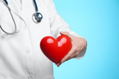Açık mavi arka planda kırmızı kalpli doktor, yakın plan.