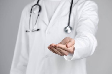 Doktor gri arka planda bir şey tutuyor, yakın plan.