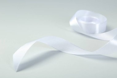Açık arkaplanda güzel beyaz kurdele makarası, yakın plan.