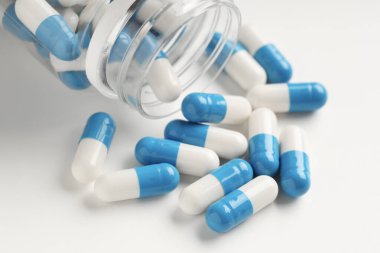 Beyaz arka planda antibiyotik hapları ve şişe, yakın plan.