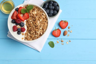Böğürtlenli tahıl gevreği ve açık mavi ahşap masada yoğurt. Metin için boşluk