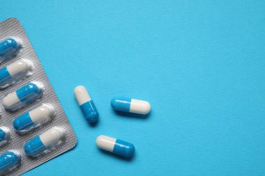 Açık mavi arka planda su toplayan antibiyotik haplar. Metin için boşluk