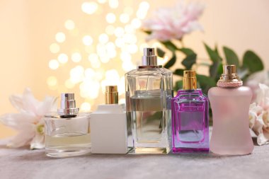 Parfüm şişeleri ve güzel nilüfer çiçekleri masa üzerinde bej arka planda bulanık ışıklarla, yakın plan