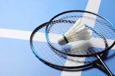 Tüylü badminton topu ve raketleri mavi arka planda, yakın plan. Metin için boşluk
