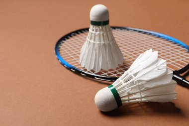 Feather badminton mekik horozu ve raket kahverengi arka planda, yakın plan