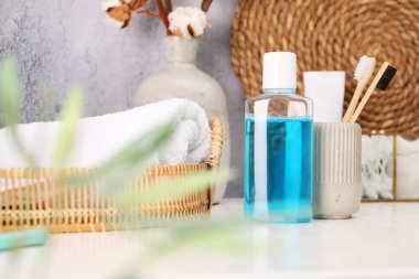 Banyodaki beyaz masada bir şişe gargara ve diş fırçası.