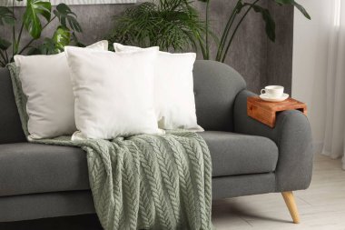 Yumuşak beyaz yastıklar ve kanepenin üzerinde battaniye.