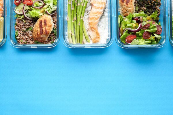 Healthy food. Different meals in glass containers on light blue background, flat lay. Space for text