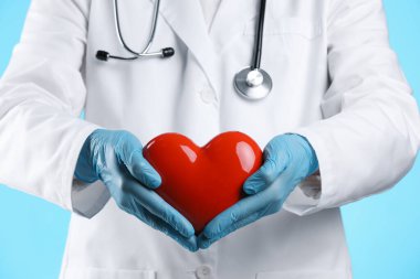Açık mavi arka planda kırmızı kalpli doktor, yakın plan.