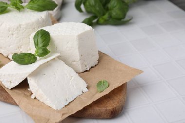 Taze ricotta (krem peynir) ve fesleğen, beyaz fayanslı masa, yakın plan. Metin için boşluk