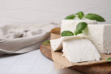 Taze ricotta (krem peynir) ve fesleğen, beyaz fayanslı masa, yakın plan. Metin için boşluk