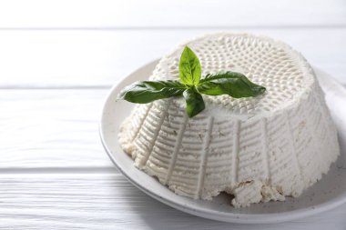 Lezzetli ricotta (krem peynir) ve fesleğen beyaz ahşap masada, yakın plan. Metin için boşluk