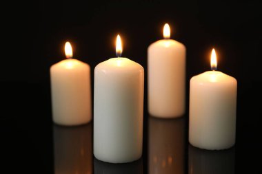 Birçok yanan mum ayna yüzeyinde siyah arkaplana karşı