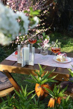 Baharda çiçekli vazo, şarap ve pasta bahçede romantik bir randevuya servis edilir.