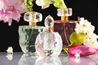 Ayna yüzeyinde siyah arka plana karşı lüks parfümler ve çiçek dekoru.