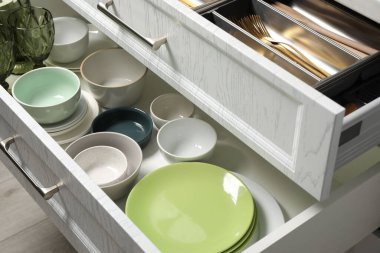 Çekmecelerde seramik bulaşık takımı ve çatal bıçak takımı.