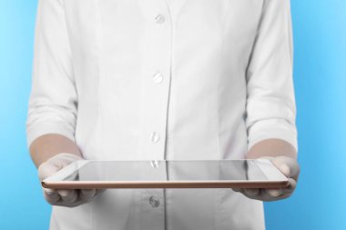 Açık mavi arkaplanda tabletli doktor, yakın plan
