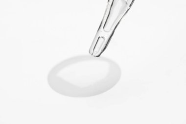 Beyaz arkaplanda cam pipet ve şeffaf sıvı, yakın plan