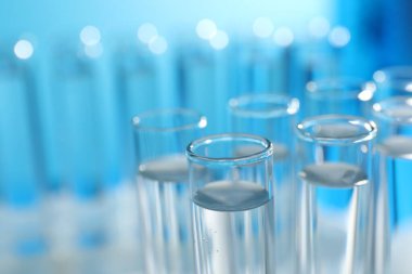 Açık mavi arka planda birçok cam test tüpü, yakın plan
